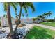 Lush front yard with palm trees, white stone accents, and a white picket fence creating a welcoming entrance at 726 Jungle Queen Way, Longboat Key, FL 34228