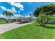 Well-maintained front yard with green lawn, palm trees, a covered carport, and a white picket fence at 726 Jungle Queen Way, Longboat Key, FL 34228