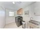 Well-lit laundry room with modern appliances, a sink, storage cabinets, and a window at 726 Jungle Queen Way, Longboat Key, FL 34228