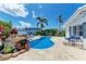 Private backyard pool with a rock waterfall feature, seating area, and mature palm trees at 726 Jungle Queen Way, Longboat Key, FL 34228