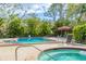 Community pool with hot tub surrounded by lush trees and ample space for residents to relax at 7674 Fairway Woods Dr # 1605, Sarasota, FL 34238