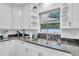 Bright kitchen features white cabinetry, dark countertops, stainless steel sink, and a window view at 946 Charlotte Ave, Sarasota, FL 34237