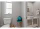 Light-filled bathroom with a white vessel sink, toilet, and a pop of color from a turquoise vase at 1201 Big Oak Ln, Sarasota, FL 34242