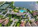 Aerial view showcasing the community clubhouse, heart-shaped pool, tennis courts, and lake at 1251 Burgos Dr # 303, Sarasota, FL 34238