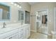 Bright bathroom features double sinks, white cabinetry, framed mirrors, and tile flooring at 1251 Burgos Dr # 303, Sarasota, FL 34238