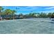 Community tennis court with well-maintained green surface, surrounding fence, and blue sky at 1251 Burgos Dr # 303, Sarasota, FL 34238