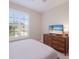 Bedroom features a view of the outdoors and a wooden dresser with a TV at 13714 Messina Loop # 202, Bradenton, FL 34211