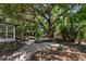 Beautiful landscaped backyard with a stone paver patio and mature tropical trees at 1857 Siesta Dr, Sarasota, FL 34239