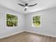 Inviting bedroom features plenty of bright natural light, wood floors, and windows showing views of lush green trees at 1857 Siesta Dr, Sarasota, FL 34239