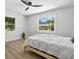 Cozy bedroom with a modern ceiling fan, wood floors and windows showing a view of lush green trees at 1857 Siesta Dr, Sarasota, FL 34239