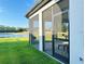View of a screened in patio with lush green yard leading to a scenic lake at 19293 Breynia Dr, Lutz, FL 33558