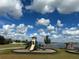 Community playground with slides offers recreation with a lovely water view under a bright blue, partly cloudy sky at 19293 Breynia Dr, Lutz, FL 33558