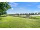 Expansive backyard with lush green grass, a serene pond, and a white fence providing privacy and scenic views at 19369 Nearpoint Dr, Venice, FL 34292