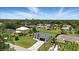 Beautiful aerial view of a single Gathering home with a gray driveway, lush green lawn, and surrounded by a beautiful tree line at 2692 Pretzel Ln, North Port, FL 34286