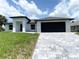 Charming one-story home with a paver driveway, black garage door, clean landscaping, and a stucco exterior at 2692 Pretzel Ln, North Port, FL 34286