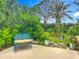 Lush backyard with mature landscaping and a blue bench for peaceful outdoor seating at 408 67Th W Ave, Bradenton, FL 34207