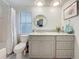 Updated bathroom featuring a marble vanity, round mirror, gray cabinets, and patterned tile flooring at 408 67Th W Ave, Bradenton, FL 34207