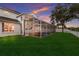 Exterior of home at dusk with a large screened-in patio, pool, and spacious green backyard at 4410 67Th Avenue E Cir, Sarasota, FL 34243