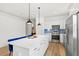 Bright kitchen featuring white cabinets, stainless steel appliances, blue backsplash, and island with seating and pendant lighting at 5004 Creekside Trl, Sarasota, FL 34243