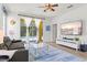Comfortable living room with a modern TV, ceiling fan, neutral decor, and a view of the pool area through sheer curtains at 5004 Creekside Trl, Sarasota, FL 34243