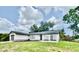 A one-story house featuring an attached garage and a dark roof against a cloudy blue sky at 5009 Jody Ave, North Port, FL 34288