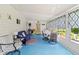 Bright sunroom with blue flooring, comfortable seating, and ample natural light from large windows with decorative curtains at 508 50Th Avenue W Plz, Bradenton, FL 34207