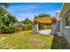 Spacious backyard with a pergola-covered patio, green lawn, and mature trees at 528 Manor Dr, Dunedin, FL 34698
