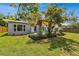 Landscaped backyard featuring a pergola, lush lawn, and gray exterior of the home at 528 Manor Dr, Dunedin, FL 34698