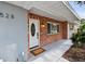 Inviting front porch featuring brick detail, a white front door, and a landscaped garden at 528 Manor Dr, Dunedin, FL 34698