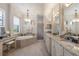 Elegant bathroom featuring a soaking tub, granite countertops, and a decorative chandelier at 5804 Mulligan Way, Lakewood Ranch, FL 34211