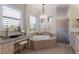 Elegant bathroom featuring a soaking tub, granite countertops, and a decorative chandelier at 5804 Mulligan Way, Lakewood Ranch, FL 34211