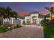 Elegant single-Gathering home featuring a paver driveway, tropical landscaping, and stone accents at 5804 Mulligan Way, Lakewood Ranch, FL 34211