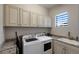 Bright laundry room with ample cabinet space, a sink, and modern appliances at 5804 Mulligan Way, Lakewood Ranch, FL 34211