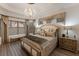 Elegant main bedroom featuring a chandelier, luxury bedding, stylish window treatments, and plank floors at 5804 Mulligan Way, Lakewood Ranch, FL 34211