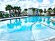 This is a community pool and sun loungers area, surrounded by tropical palm trees and a lovely blue sky at 6253 Whetstone Ct, Palmetto, FL 34221