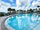 Inviting community pool surrounded by lush landscaping, lounge chairs, and clear blue sky at 6253 Whetstone Ct, Palmetto, FL 34221