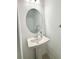 Compact powder room features a pedestal sink with an oval mirror, complemented by minimalist decor and neutral tones at 6253 Whetstone Ct, Palmetto, FL 34221
