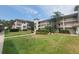 Three-story condo building with balconies, a lush green lawn and mature palm trees at 6507 Stone River Rd # 302, Bradenton, FL 34203