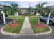 Condo building entrance featuring sidewalk, manicured lawn and mature landscaping with palm trees at 6507 Stone River Rd # 302, Bradenton, FL 34203
