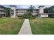 Well-maintained condo building with lush landscaping, palm trees, and a welcoming walkway at 6507 Stone River Rd # 302, Bradenton, FL 34203