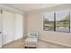 Well-lit bedroom featuring a light blue chair and ottoman plus a window overlooking lush landscaping at 6512 Grand Estuary Trl # 101, Bradenton, FL 34212