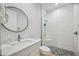 Bright bathroom featuring a walk-in shower, vanity, and round mirror, combining style and functionality at 103 Graham Se St, Port Charlotte, FL 33952