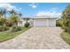 A beautiful home with a three car garage and paver driveway is surrounded by lush landscaping at 103 Graham Se St, Port Charlotte, FL 33952