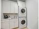 Well-equipped laundry room with white cabinets, sink, and stacked washer/dryer maximizing space and convenience at 103 Graham Se St, Port Charlotte, FL 33952