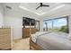 Bright main bedroom featuring travertine floors, ceiling fan, tray ceiling, and scenic views of the backyard and waterfront at 103 Graham Se St, Port Charlotte, FL 33952