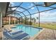 Refreshing pool area with lounge chairs, enclosed in a screen, overlooking lush landscaping and waterfront views at 103 Graham Se St, Port Charlotte, FL 33952