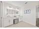 Bright bathroom featuring dual sinks, vanity, and large, illuminated mirror at 18307 White Fang Ct, Parrish, FL 34219