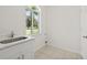 Bright laundry room featuring a window, tile flooring, a sink and a white storage cabinet at 18307 White Fang Ct, Parrish, FL 34219