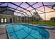 Screened-in pool at sunset with integrated spa, sun-drenched deck, and a beautiful view of the lush lawn at 18307 White Fang Ct, Parrish, FL 34219