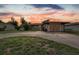 Exterior view of a single-story home with a large driveway and partially boarded-up garage at sunset at 268 Alsace Ave, Venice, FL 34293